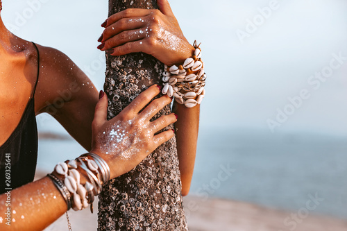 Fotografía close up of young woman hands wearing boho accessories made of cowry shells