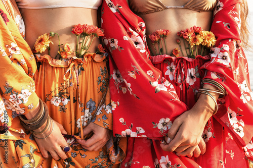 close up of two beautiful stylish boho model in colorful costumes with flowers photo