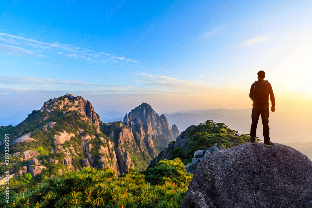 Obraz premium Young happy backpacker on top of a mountain enjoying valley view