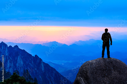 Young happy backpacker on top of a mountain enjoying valley view