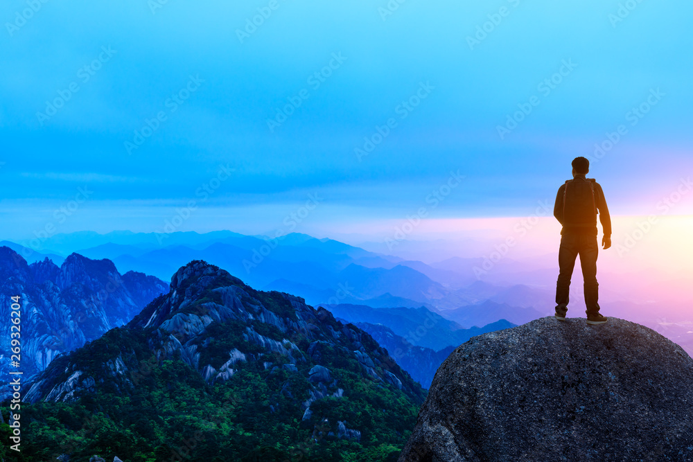 Young happy backpacker on top of a mountain enjoying valley view