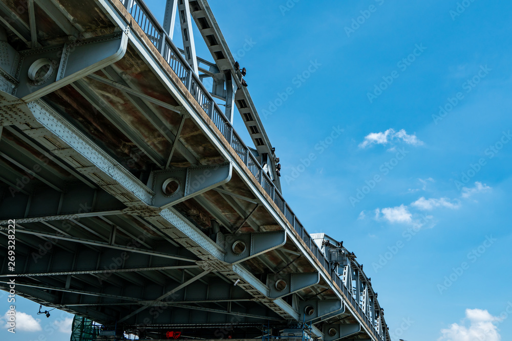 Steel bridge structure against blue sky and white clouds. Iron bridge engineering construction. Strong and strength metal bridge. Road bridge architecture. Infrastructure.