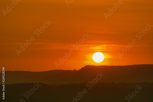 Beautiful nature landscape of mountain with sunset sky and clouds. Scenery of mountain layer at dusk with big round sun. Natural background. Orange and red sky in the evening. Sunset sky background.