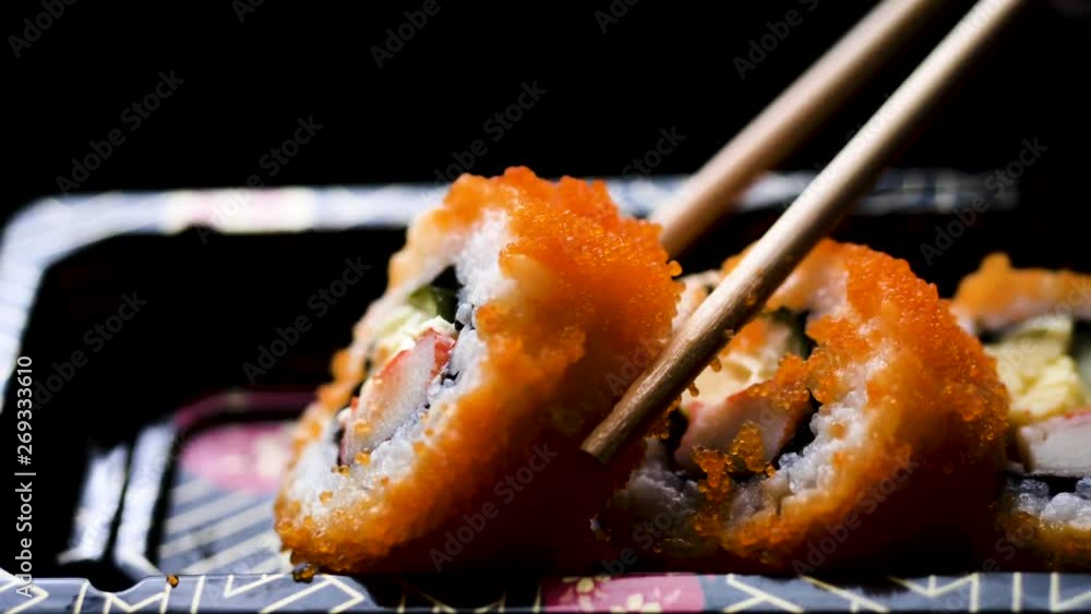 Kid hand learning io use chopsticks with california roll in takeaway box, slow motion. Kid hand learning io use chopsticks with california roll in takeaway box, slow motion.