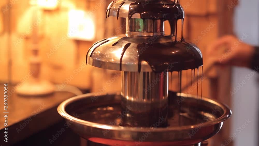 chocolate fountain. the man prepares the fountain to serve. close up chocolate fountain. the man prepares the fountain to serve. close up
