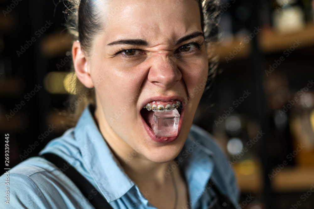 girl holds teeth with ice cube with braces aggressively girl holds teeth with ice cube with braces aggressively