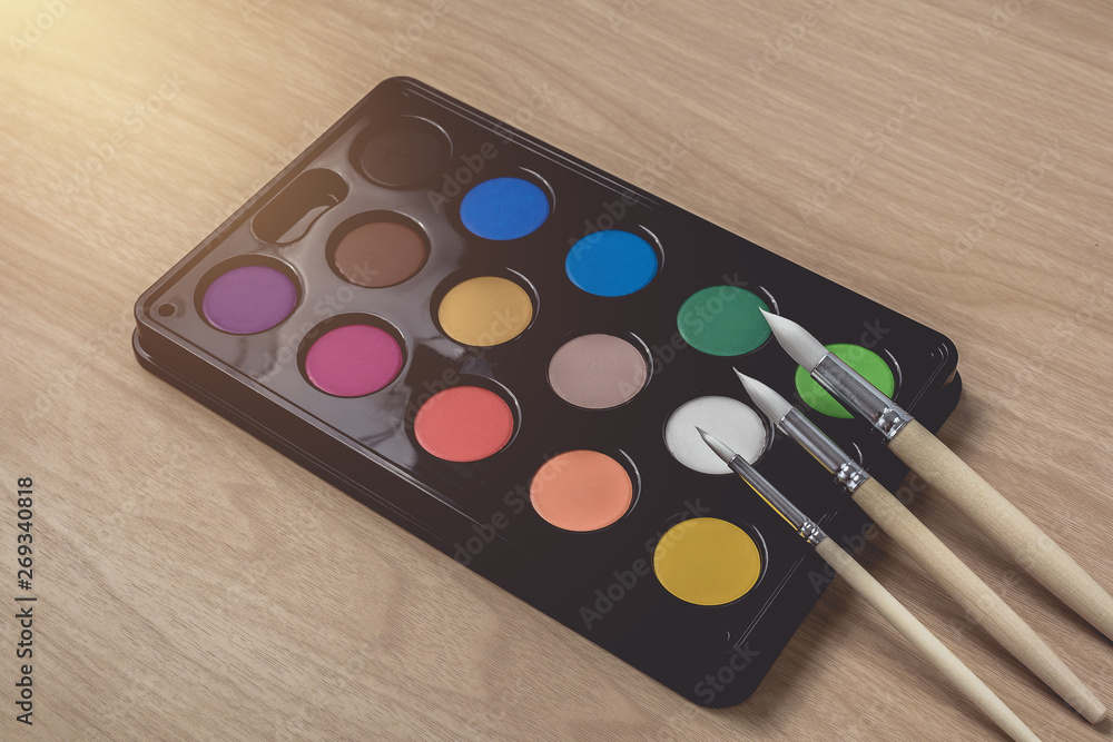 Paintbrush and Watercolor palette on brown wood table.using for Arts and Education background Paintbrush and Watercolor palette on brown wood table.using for Arts and Education background