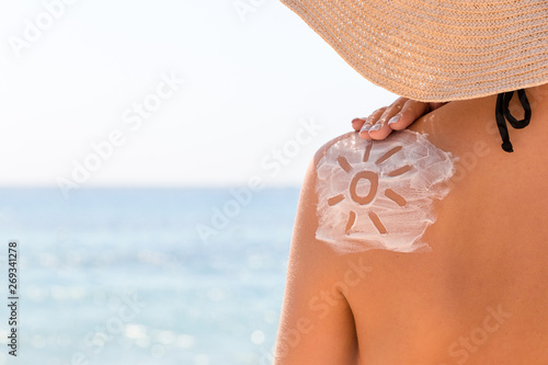 Obraz na płótnie Sunscreen lotion in sun shape on tanned woman's shoulder