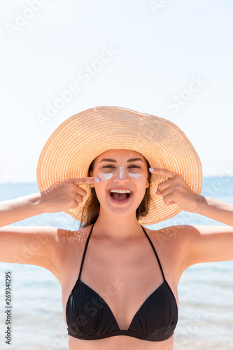 Smiling woman in hat is applying sunscreen on her face. Indian style © sosiukin