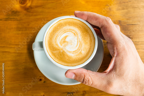 A cup of coffee in a cafe and a man's hands. Close-up of man's hands, sitting with cup of coffee, overhead