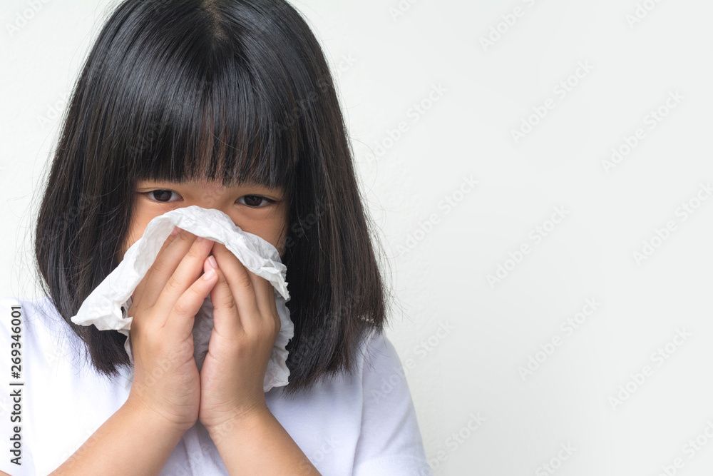 Portrait of unhealthy sick Asia kid girl standing with napkin close her nose from allergy or rhinitis. Unhappy ill child suffering from running nose and sneezing and blow her nose on white background Portrait of unhealthy sick Asia kid girl standing with napkin close her nose from allergy or rhinitis. Unhappy ill child suffering from running nose and sneezing and blow her nose on white background
