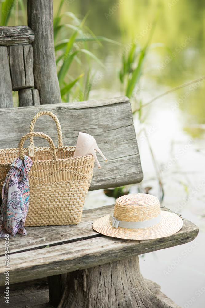 Thatch straw hat with bag basket on a wooden bench in summer women accessories