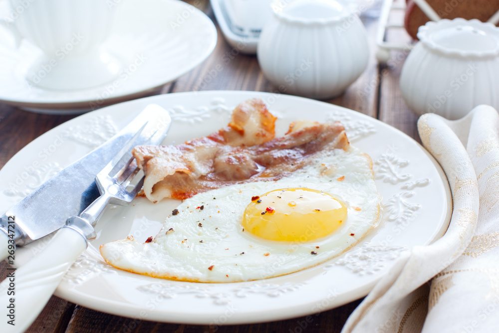 Traditional English breakfast of fried eggs with bacon on a wooden table, horizontal Traditional English breakfast of fried eggs with bacon on a wooden table, horizontal