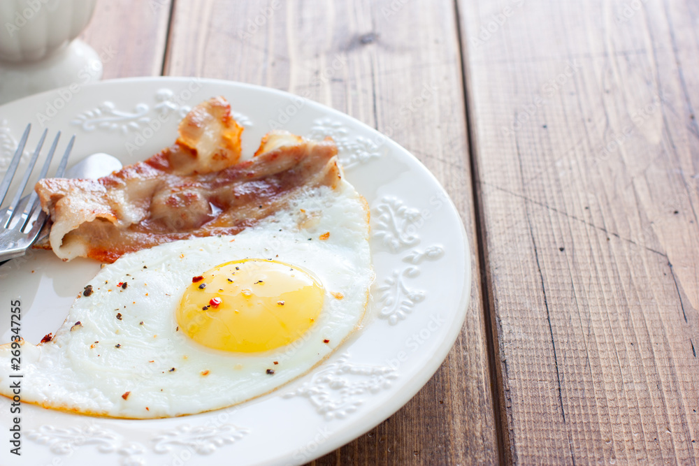 Traditional English breakfast of fried eggs with bacon on a wooden table, horizontal, place for text Traditional English breakfast of fried eggs with bacon on a wooden table, horizontal, place for text