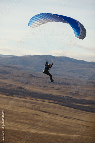 Speedflyer flies under the canopy of the parachute against the backdrop of the autumn landscape close-up.