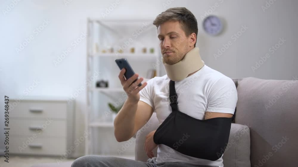 Man in arm sling and foam cervical collar talking on cellphone, upset with news Man in arm sling and foam cervical collar talking on cellphone, upset with news