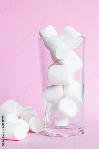 White marshmallows in the glass on pink background