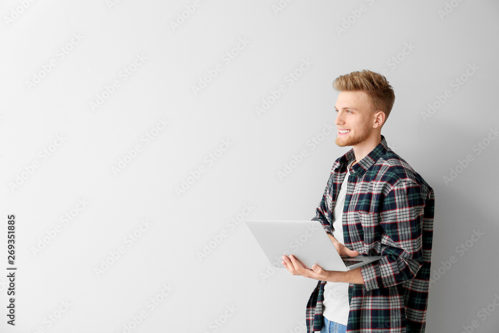 Handsome young man with laptop on light background Handsome young man with laptop on light background