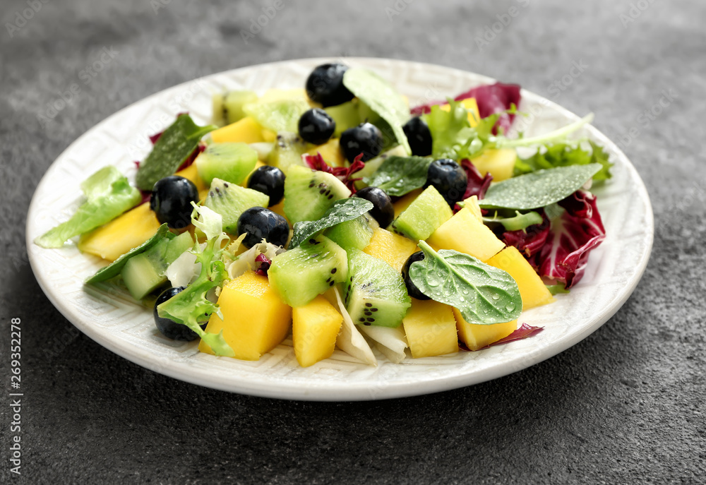 Plate with tasty mango salad on grey background