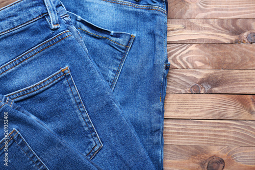 Stylish jeans pants on wooden background