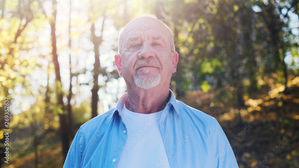 Portrait of senior man with a beard smiling while standing outside in sunlight. Portrait of senior man with a beard smiling while standing outside in sunlight.