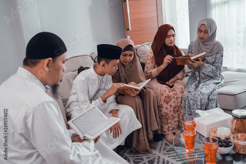 portrait of muslim family reading quran together in livingroom