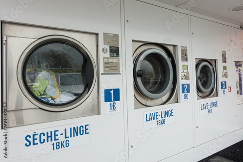 A row of large load washing machines and driers are available for public use outside a supermarket in France photo