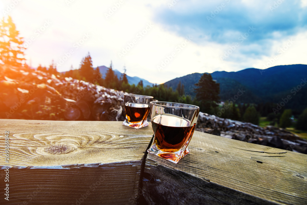shot of whiskey at sunset dramatic sky on mountain landscape background