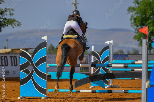 Young rider jumping over the obstacles during the horse jumping competition