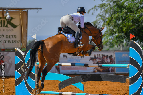 Young rider jumping over the obstacles during the horse jumping competition