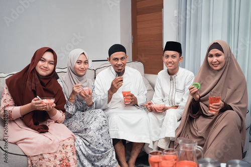 group of happy muslim having dinner at home looking to camera during ramadan celebration, break fasting