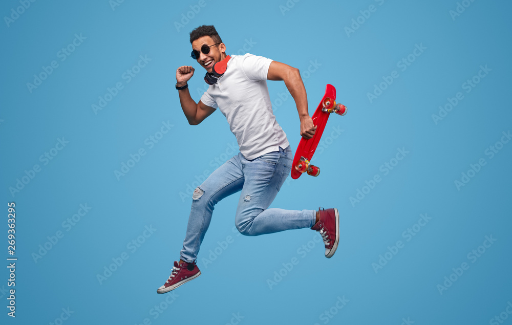 Obraz premium Black hipster with skateboard jumping and smiling