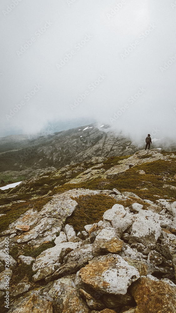 Paisaje con niebla y persona en cima de montaña