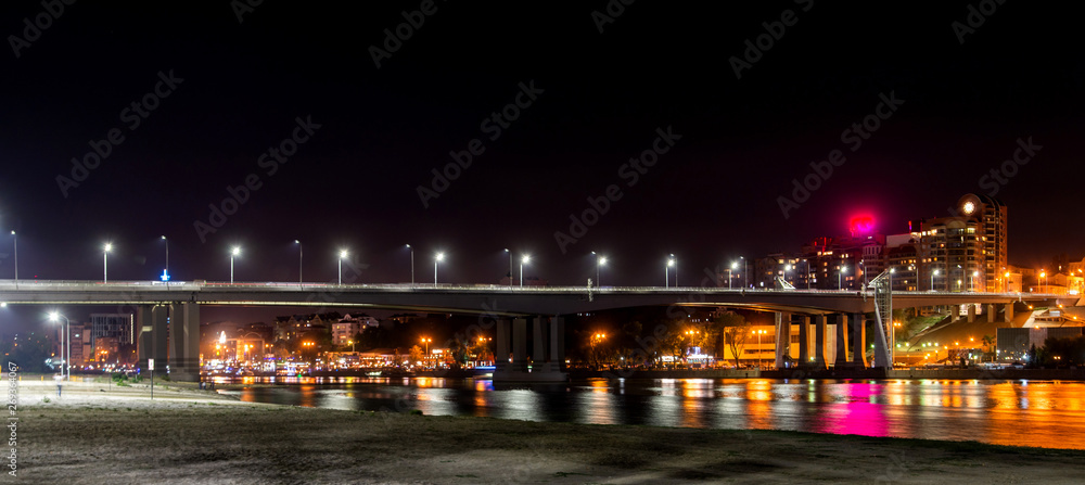 Playground on the sandy beach. Bridge over the river and night city on the background.