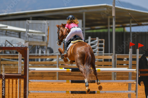 Young rider jumping over the obstacles during the horse jumping competition