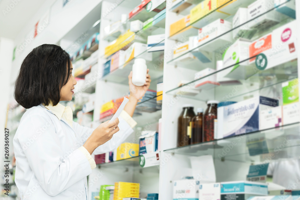 Pharmacist Asian female filling prescription medication  in pharmacy for customer or patient. small business, medicine, pharmaceutics, health care, lifestyle and people concept