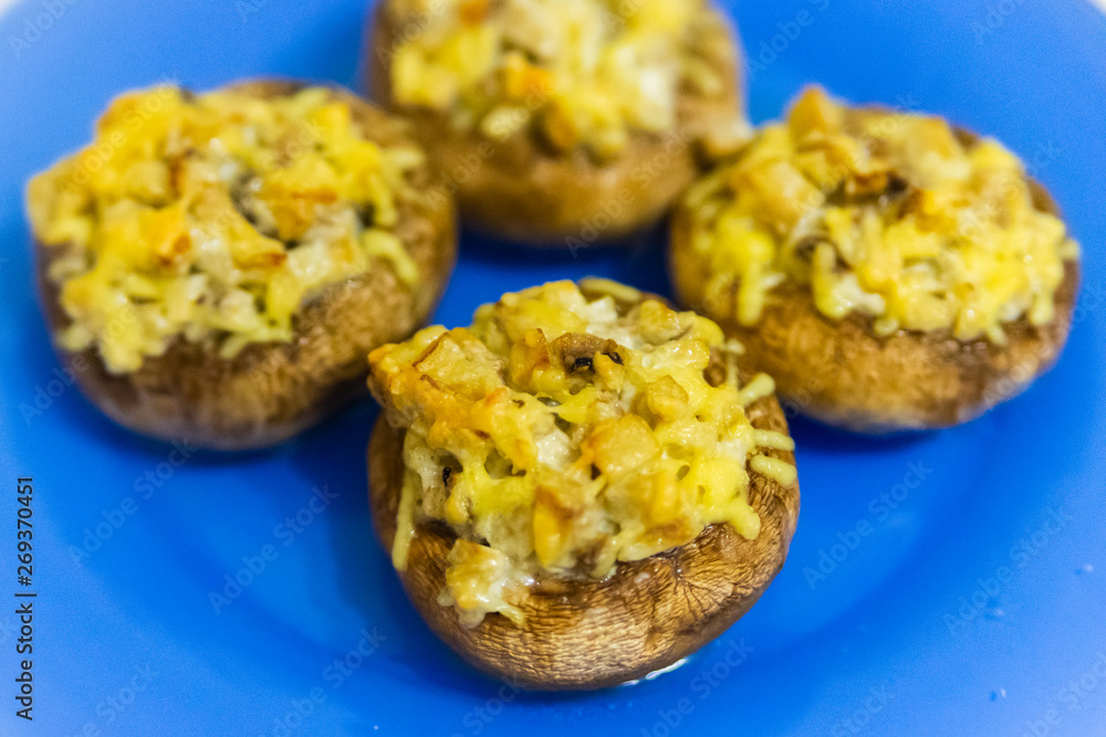 Grilled mushrooms stuffed with cheese on blue plate Grilled mushrooms stuffed with cheese on blue plate