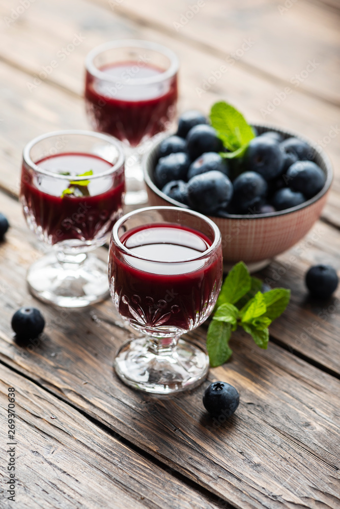 Sweet blueberry liqueur on the wooden table Sweet blueberry liqueur on the wooden table