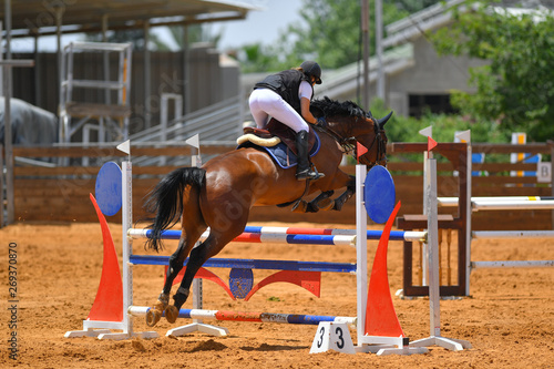 Young rider jumping over the obstacles during the horse jumping competition