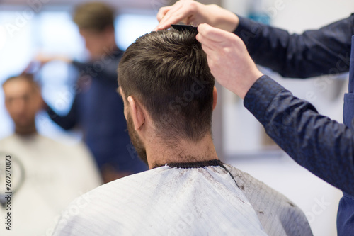 grooming, hairdressing and people concept - male client and hairdresser cutting hair at barbershop