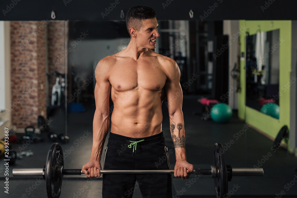 Young muscular man in the gym doing exercise Young muscular man in the gym doing exercise