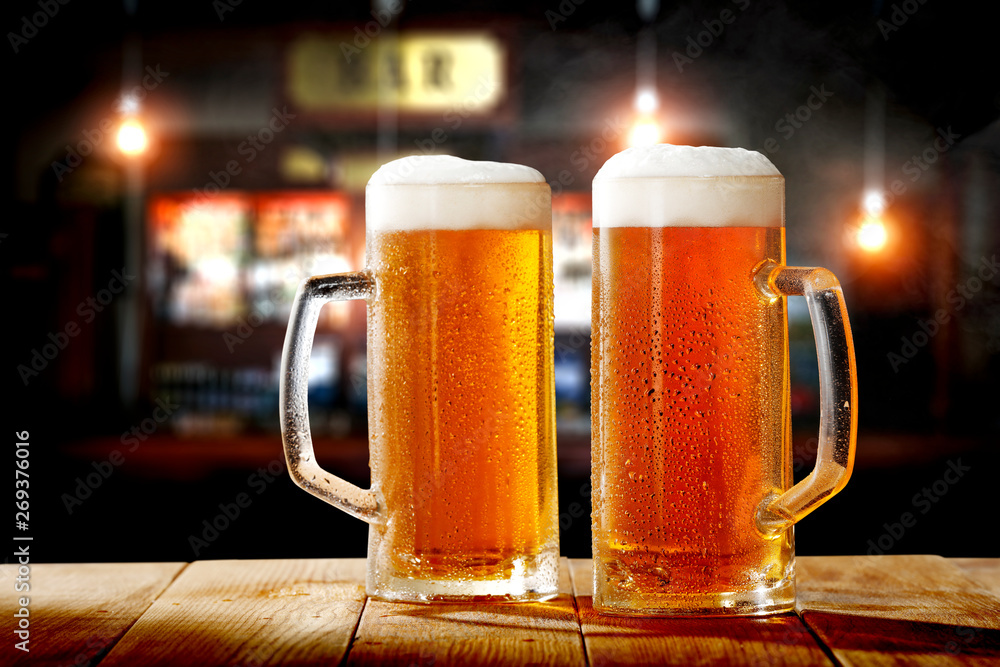 Cold fresh beer in glass on wooden table and free space for your decoration. Blurred bar interior Cold fresh beer in glass on wooden table and free space for your decoration. Blurred bar interior