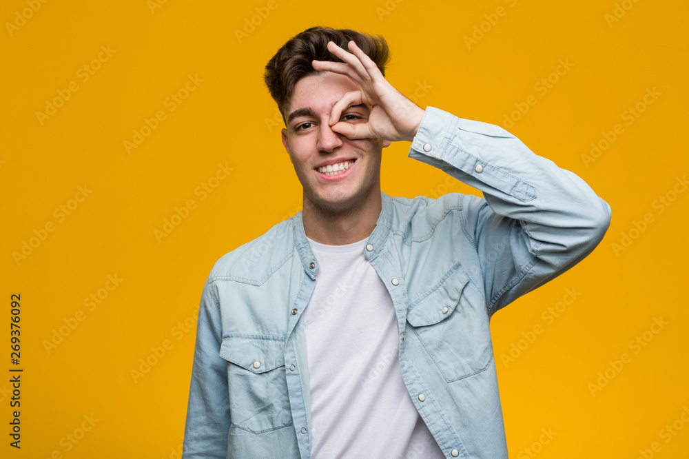 Young handsome student wearing a denim shirt excited keeping ok gesture on eye. Young handsome student wearing a denim shirt excited keeping ok gesture on eye.