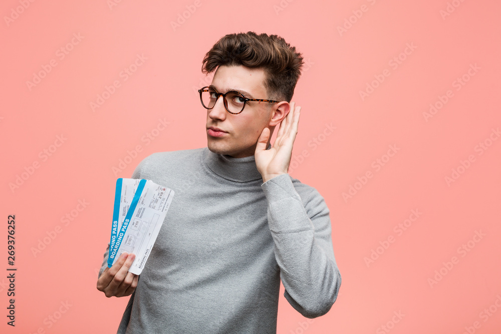 Young cool man holding an air tickets trying to listening a gossip. Young cool man holding an air tickets trying to listening a gossip.