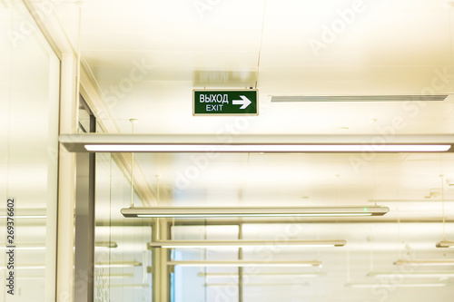 Signboard saying  Exit  on the ceiling in the bright spacious empty office in an office building. Open space office  concept.