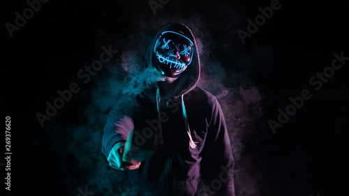 Fotografie Chico con mascara de luces sobre un fondo negro con humo