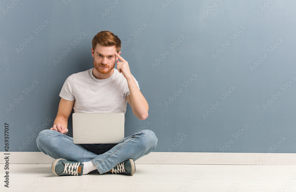 Young redhead student man sitting on the floor thinking about an idea. He is holding a laptop. Young redhead student man sitting on the floor thinking about an idea. He is holding a laptop.