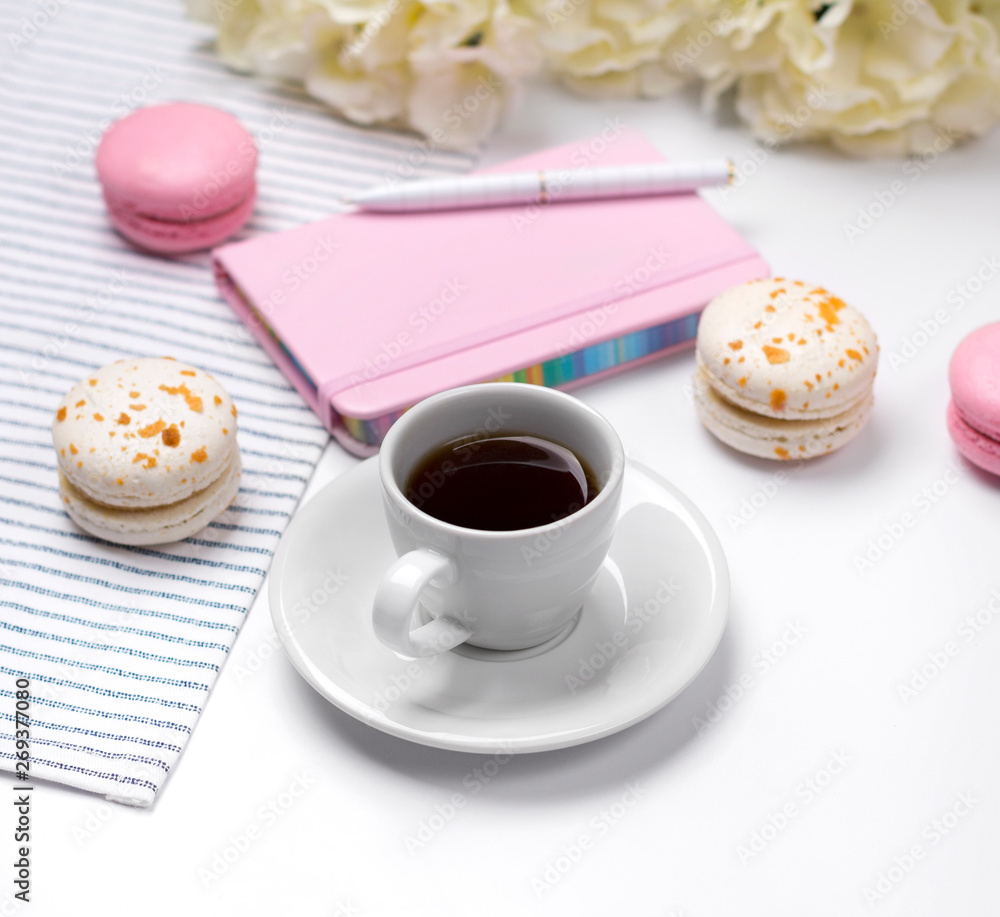 Pink notebook, pen, macaroons, coffee and flowers on white background. Pink notebook, pen, macaroons, coffee and flowers on white background.