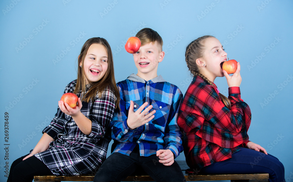 Fototapeta premium Boy and girls friends eat apple snack while relaxing. Teens with healthy snack. Healthy dieting and vitamin nutrition. School snack concept. Group cheerful teenagers communicating and eating apples