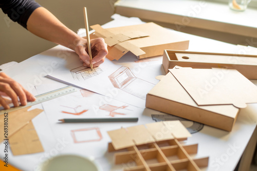 Hands designer draws a sketch of paper packaging. Creative development of ecological boxes.  